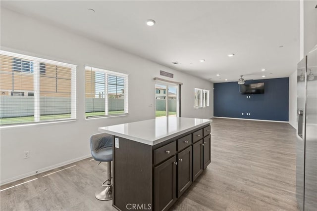 26627 Pearl Blossom Way, Menifee, CA 92585 - kitchen featuring light wood-style flooring, a kitchen island, light countertops, a kitchen bar, and recessed lighting