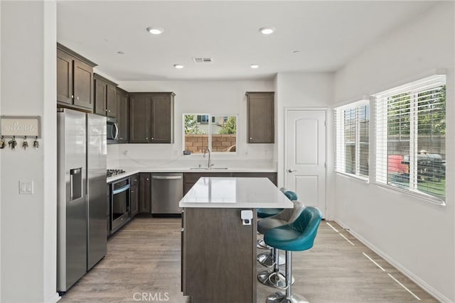 26627 Pearl Blossom Way, Menifee, CA 92585 - kitchen with stainless steel appliances, dark brown cabinetry, a breakfast bar, a center island, and light countertops