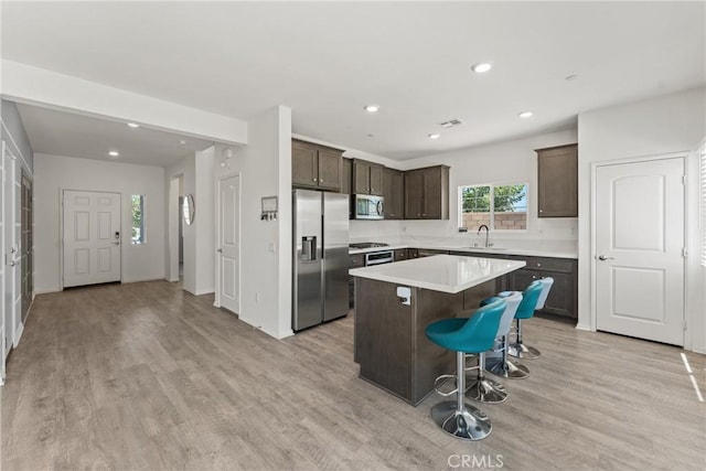 26627 Pearl Blossom Way, Menifee, CA 92585 - kitchen with appliances with stainless steel finishes, dark brown cabinets, a kitchen island, recessed lighting, and light wood-type flooring