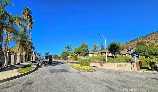 940 N Silent Ranch Dr, Glendora, CA 91741 - view of asphalt road featuring street lights, a mountain view, curbs, a gate, and a gated entry