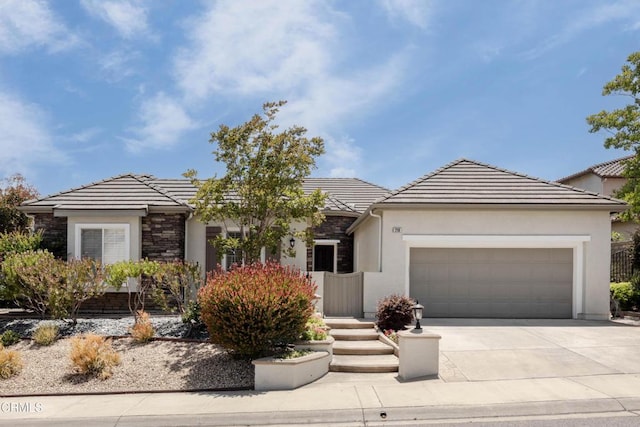 219 Via Rebecca, Thousand Oaks, CA 91320 - view of front of house featuring stone siding, a garage, concrete driveway, a tile roof, and stucco siding