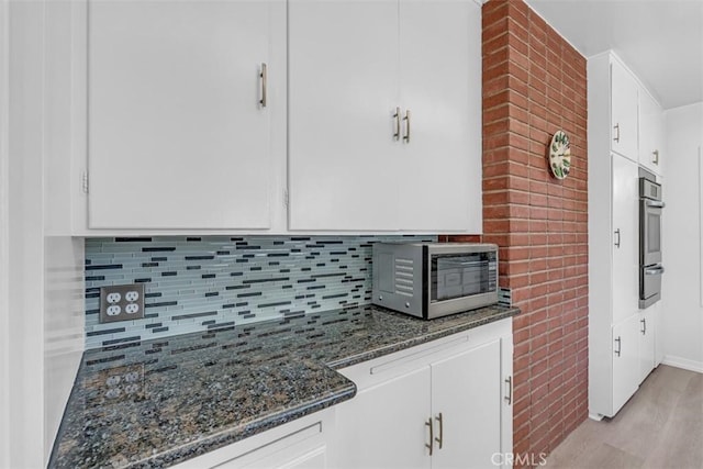 1011 Portola Dr, Arcadia, CA 91007 - kitchen with appliances with stainless steel finishes, white cabinetry, tasteful backsplash, dark stone countertops, and light wood-style flooring