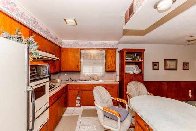 17480 Fontlee Ln, Fontana, CA 92335 - kitchen with white appliances, light countertops, brown cabinets, and under cabinet range hood