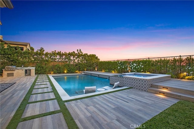 2526 N La Colina Ct, Orange, CA 92867 - pool at dusk featuring an outdoor kitchen, a fenced backyard, a pool with connected hot tub, and a deck