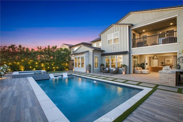 2526 N La Colina Ct, Orange, CA 92867 - back of property at dusk featuring board and batten siding, a pool with connected hot tub, a balcony, a deck, and stucco siding