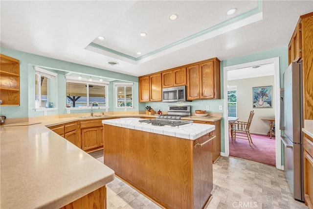 929 9th St, Williams, CA 95987 - kitchen with stainless steel appliances, a tray ceiling, a kitchen island, recessed lighting, and brown cabinets