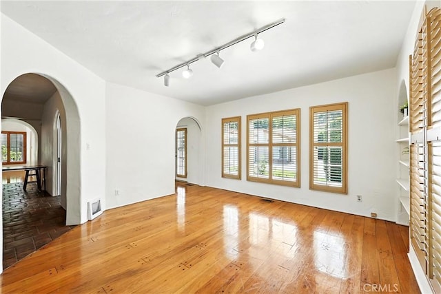 408 N Mccadden Pl, Los Angeles, CA 90004 - unfurnished living room with arched walkways, rail lighting, and hardwood / wood-style flooring