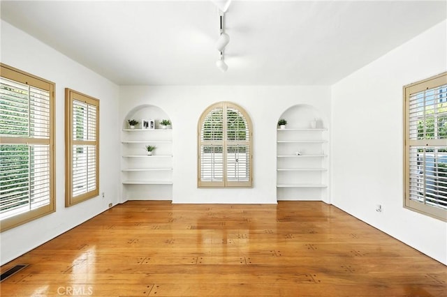408 N Mccadden Pl, Los Angeles, CA 90004 - empty room with built in shelves, hardwood / wood-style floors, and track lighting
