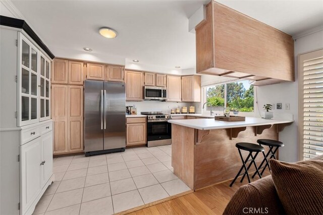 5231 Hiram Ln, Irvine, CA 92603 - kitchen featuring appliances with stainless steel finishes, a peninsula, light countertops, a kitchen breakfast bar, and glass insert cabinets