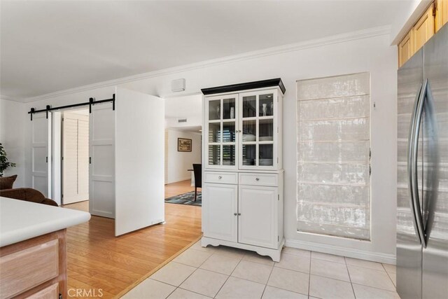 5231 Hiram Ln, Irvine, CA 92603 - kitchen featuring freestanding refrigerator, a barn door, ornamental molding, light tile patterned floors, and glass insert cabinets