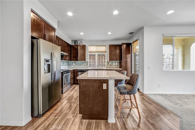 70 Linden Ln, Temple City, CA 91780 - kitchen with stainless steel appliances, a kitchen island, dark brown cabinets, a breakfast bar, and decorative backsplash