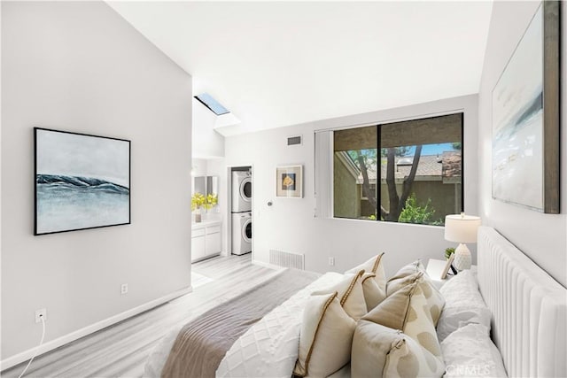 90 Lakepines Unit 5B, Irvine, CA 92620 - bedroom with stacked washer and clothes dryer, light wood-style floors, vaulted ceiling, a skylight, and ensuite bath