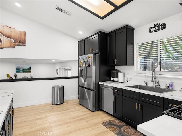 1324 Windermere Ct, Palmdale, CA 93551 - kitchen with stainless steel appliances, dark cabinetry, light wood-type flooring, light countertops, and vaulted ceiling