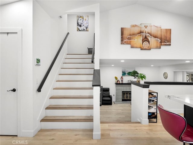 1324 Windermere Ct, Palmdale, CA 93551 - stairway featuring wood finished floors, a brick fireplace, recessed lighting, and lofted ceiling