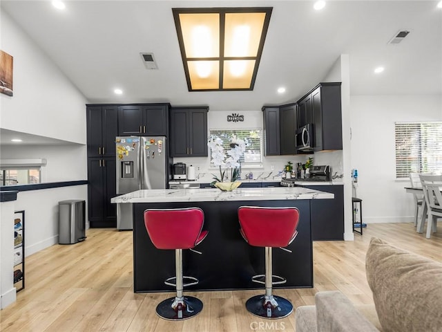 1324 Windermere Ct, Palmdale, CA 93551 - kitchen featuring appliances with stainless steel finishes, a center island, light stone countertops, dark cabinets, and recessed lighting