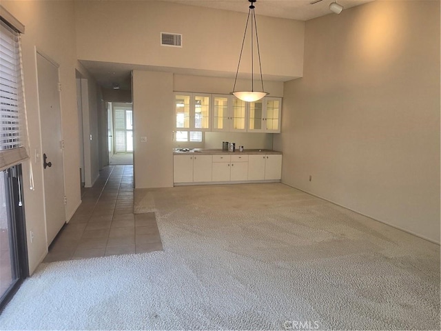 8566 Larkhall Cir Unit 808A, Huntington Beach, CA 92646 - kitchen featuring light carpet, white cabinets, glass insert cabinets, pendant lighting, and light tile patterned flooring