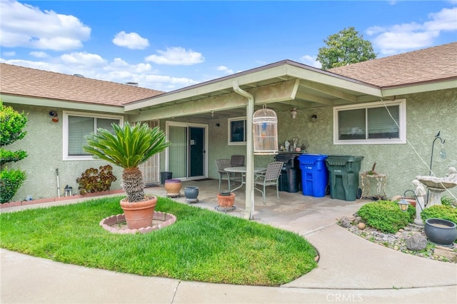 17655 Vine Ct, Fontana, CA 92335 - view of exterior entry featuring stucco siding, a patio, a lawn, and roof with shingles