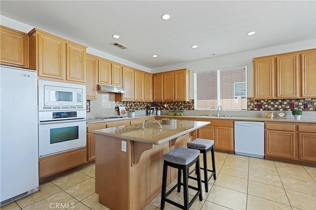 750 Multnomah Ct, San Jacinto, CA 92582 - kitchen featuring white appliances, tasteful backsplash, light tile patterned floors, a center island, and a kitchen bar
