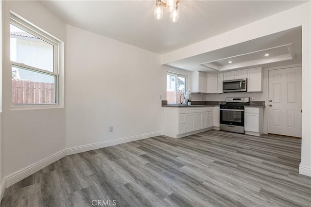 14791 Mountain High Dr, Fontana, CA 92337 - kitchen featuring appliances with stainless steel finishes, a tray ceiling, light wood finished floors, white cabinets, and recessed lighting