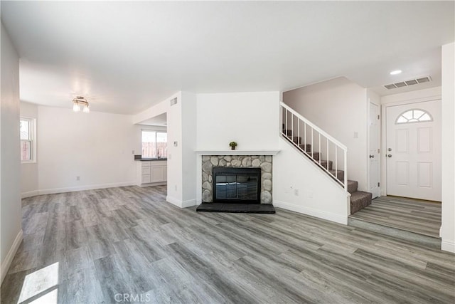 14791 Mountain High Dr, Fontana, CA 92337 - unfurnished living room featuring wood finished floors, stairs, and a stone fireplace