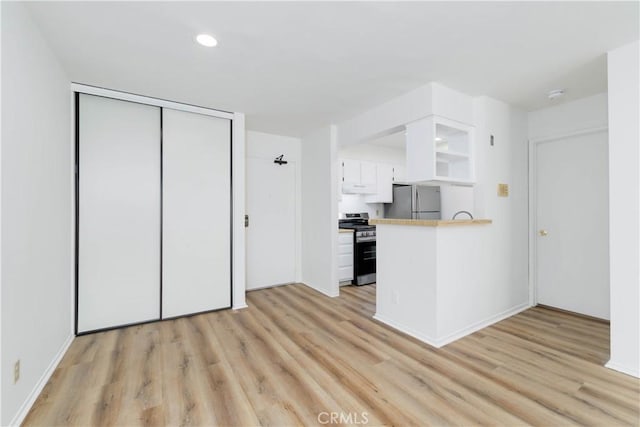 1119 Albany St Unit 226, Los Angeles, CA 90015 - kitchen with stainless steel appliances, light wood finished floors, white cabinetry, a peninsula, and recessed lighting