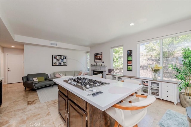 5560 Via Cantada, Yorba Linda, CA 92887 - kitchen with stainless steel gas cooktop, a tiled fireplace, light countertops, open floor plan, and a center island
