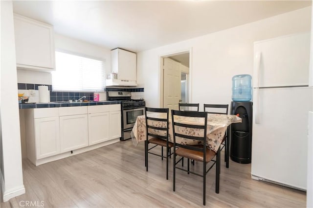 285 W 9th St, San Pedro, CA 90731 - kitchen with stainless steel range with gas cooktop, freestanding refrigerator, tile counters, white cabinets, and light wood-type flooring