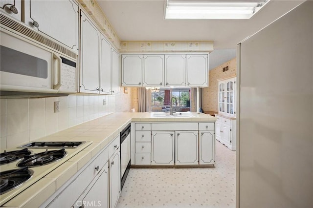 19309 Flowers Ct, Newhall, CA 91321 - kitchen with white appliances, tile countertops, a peninsula, and tasteful backsplash