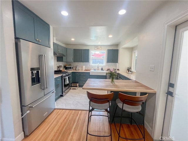 4574 Whaley Ave, Long Beach, CA 90807 - kitchen with high quality appliances, a peninsula, a breakfast bar, tasteful backsplash, and blue cabinetry