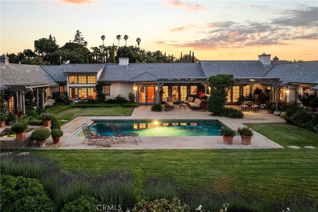 1559 Rolling Hills Rd, Santa Ynez, CA 93460 - back of property at dusk featuring a pergola, french doors, a chimney, an outdoor pool, and a lawn