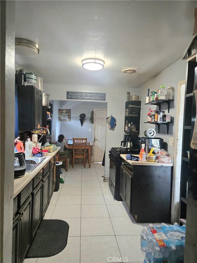 12431 Merrill St, Garden Grove, CA 92840 - kitchen featuring black range with gas cooktop, light tile patterned flooring, light countertops, and dark cabinetry