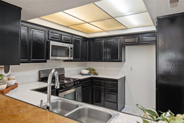 950 Cagney Ln Unit 107, Newport Beach, CA 92663 - kitchen with appliances with stainless steel finishes, dark cabinets, and light countertops