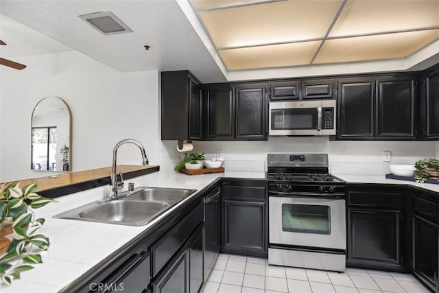 950 Cagney Ln Unit 107, Newport Beach, CA 92663 - kitchen featuring appliances with stainless steel finishes, dark cabinetry, tile countertops, ceiling fan, and light tile patterned floors