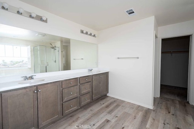 4389 Condor Ave, Fontana, CA 92336 - bathroom featuring a stall shower, wood finished floors, double vanity, and a walk in closet