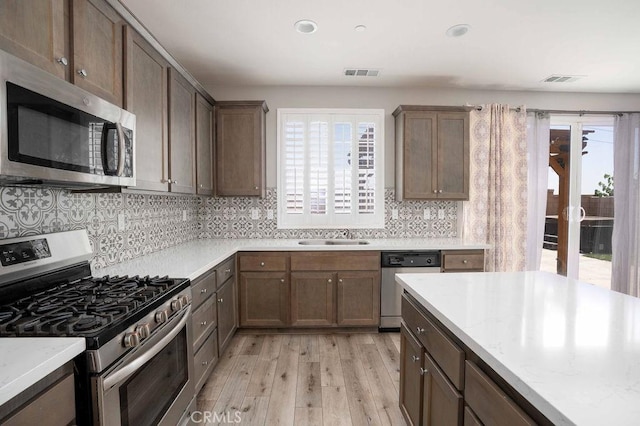 4389 Condor Ave, Fontana, CA 92336 - kitchen featuring appliances with stainless steel finishes, light wood-type flooring, backsplash, recessed lighting, and light stone countertops
