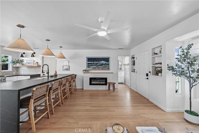 6335 Lorca Dr, San Diego, CA 92115 - kitchen with open shelves, light wood-style floors, dark countertops, a glass covered fireplace, and plenty of natural light
