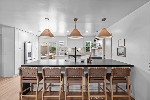 6335 Lorca Dr, San Diego, CA 92115 - kitchen featuring stainless steel fridge with ice dispenser, white cabinetry, a breakfast bar area, light wood-style floors, and recessed lighting