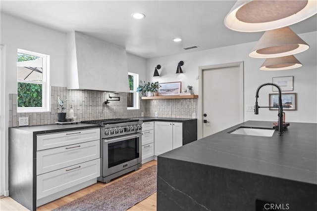 6335 Lorca Dr, San Diego, CA 92115 - kitchen with high end range, dark countertops, premium range hood, light wood finished floors, and tasteful backsplash