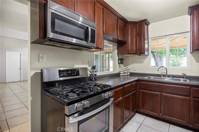 2616 Lynwood St, Bakersfield, CA 93306 - kitchen with appliances with stainless steel finishes, dark countertops, light tile patterned flooring, and reddish brown cabinets