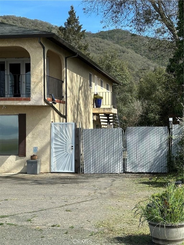 6896 Frontage Rd, Lucerne, CA 95458 - view of side of property with stucco siding, a mountain view, a balcony, and a gate