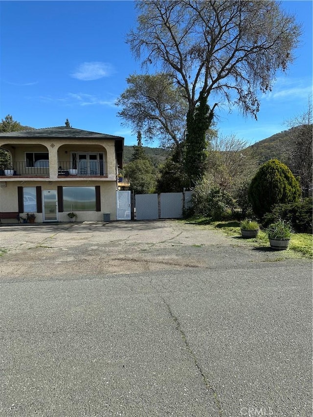 6896 Frontage Rd, Lucerne, CA 95458 - view of front of home featuring stucco siding, a gate, and a balcony