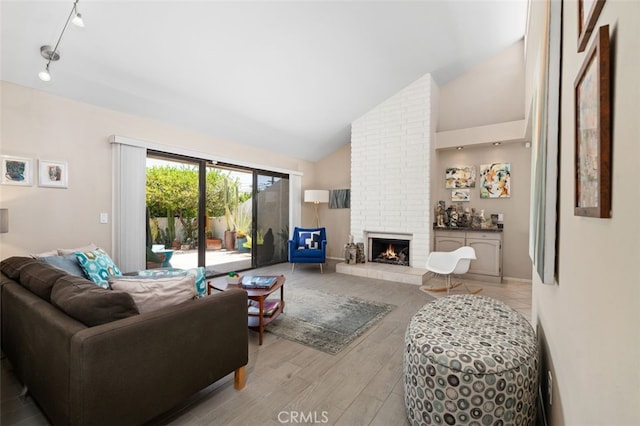 72760 Sage Ct, Palm Desert, CA 92260 - living area featuring light wood finished floors, a fireplace, high vaulted ceiling, and rail lighting