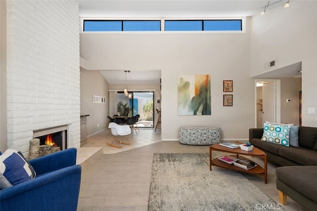 72760 Sage Ct, Palm Desert, CA 92260 - living room with a towering ceiling, wood finished floors, rail lighting, and a fireplace