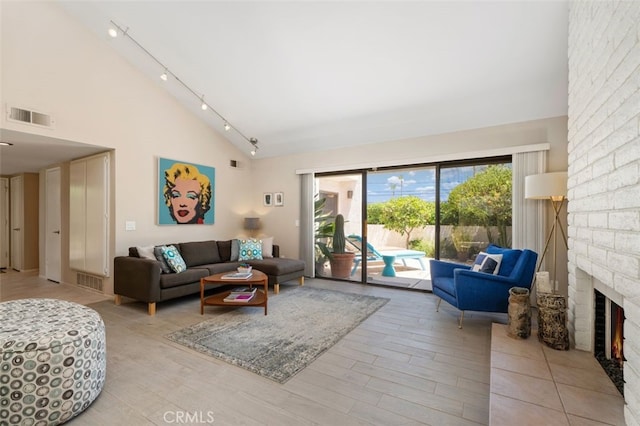 72760 Sage Ct, Palm Desert, CA 92260 - living room featuring rail lighting, a fireplace, wood finished floors, and high vaulted ceiling