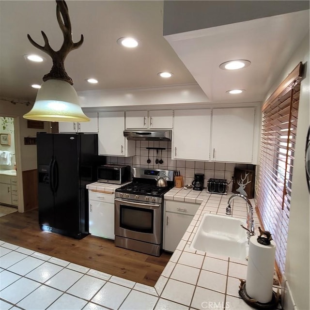 1126 Aleutian Dr, Lake Arrowhead, CA 92352 - kitchen with tile counters, appliances with stainless steel finishes, under cabinet range hood, white cabinets, and decorative backsplash