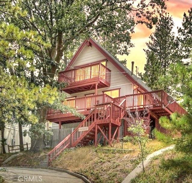 1126 Aleutian Dr, Lake Arrowhead, CA 92352 - back of house at dusk with stairs, a deck, and a balcony