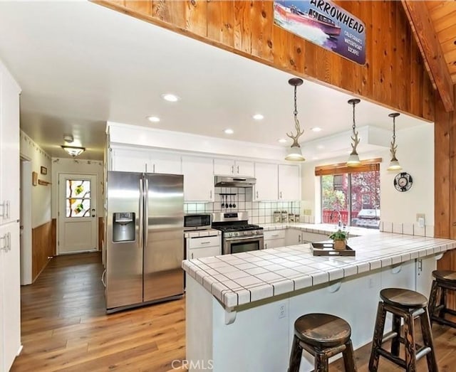 1126 Aleutian Dr, Lake Arrowhead, CA 92352 - kitchen with stainless steel appliances, under cabinet range hood, a peninsula, healthy amount of natural light, and recessed lighting