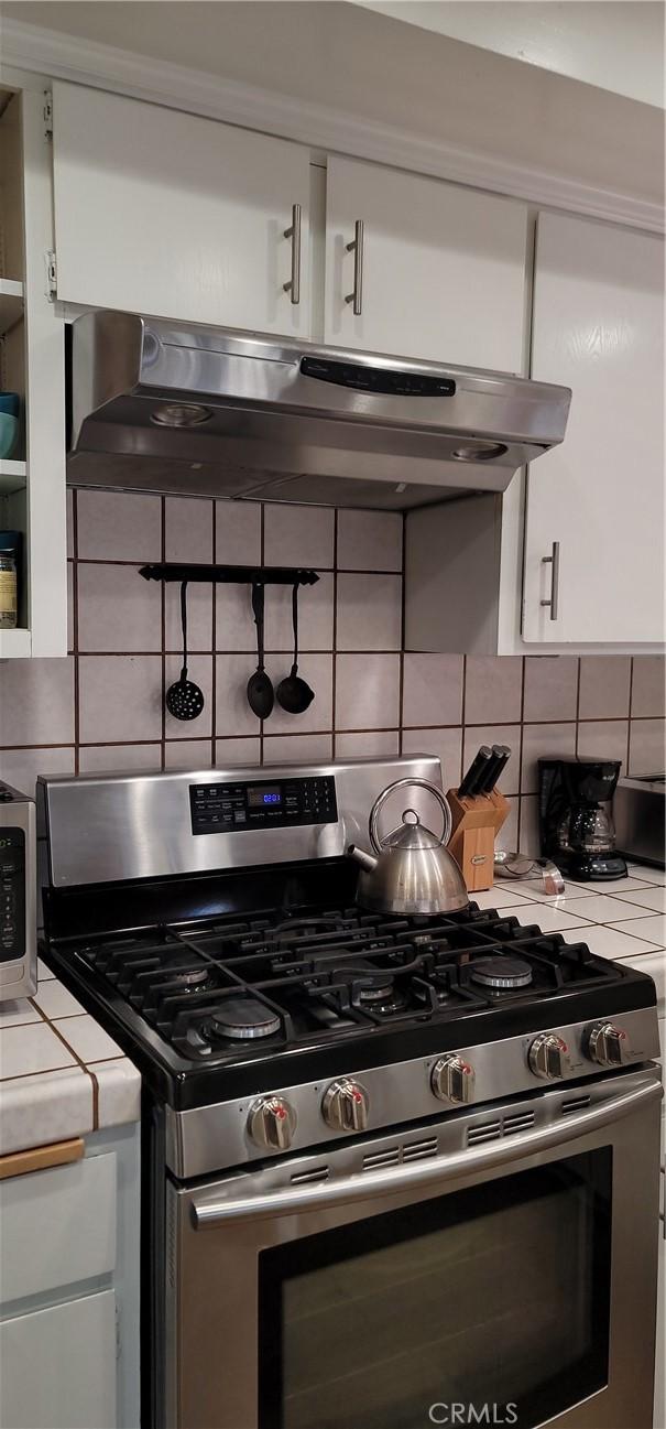 1126 Aleutian Dr, Lake Arrowhead, CA 92352 - kitchen with gas range, tasteful backsplash, and white cabinetry
