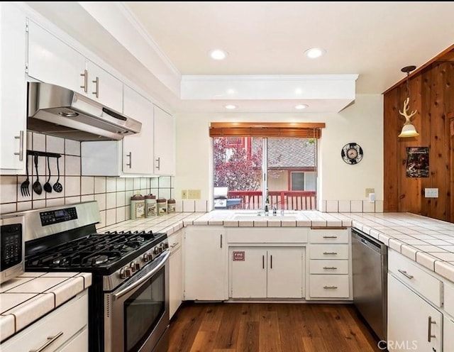 1126 Aleutian Dr, Lake Arrowhead, CA 92352 - kitchen with appliances with stainless steel finishes, under cabinet range hood, tile countertops, backsplash, and crown molding