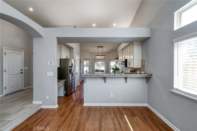 2925 E El Paso Ave, Fresno, CA 93720 - kitchen with appliances with stainless steel finishes, a peninsula, wood finished floors, a breakfast bar area, and light stone countertops